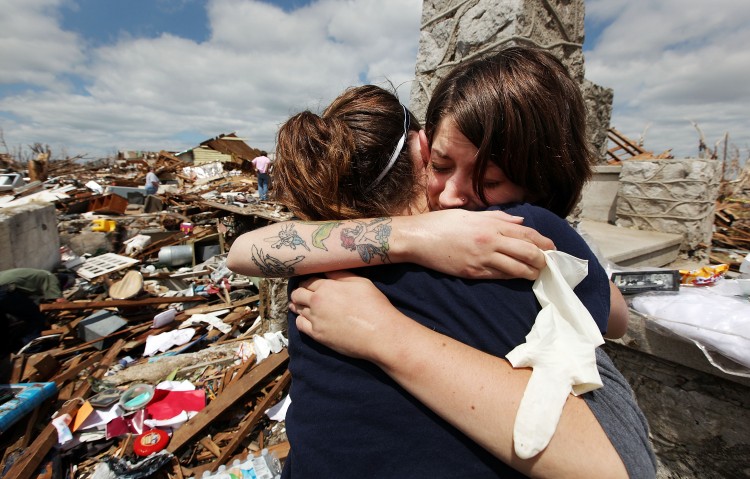 In this file photo, Shandie Spencer (R) hugs a volunteer while recovering items from the basement of her destroyed home after the Joplin, Mo tornadoes. (Mario Tama/Getty Images)