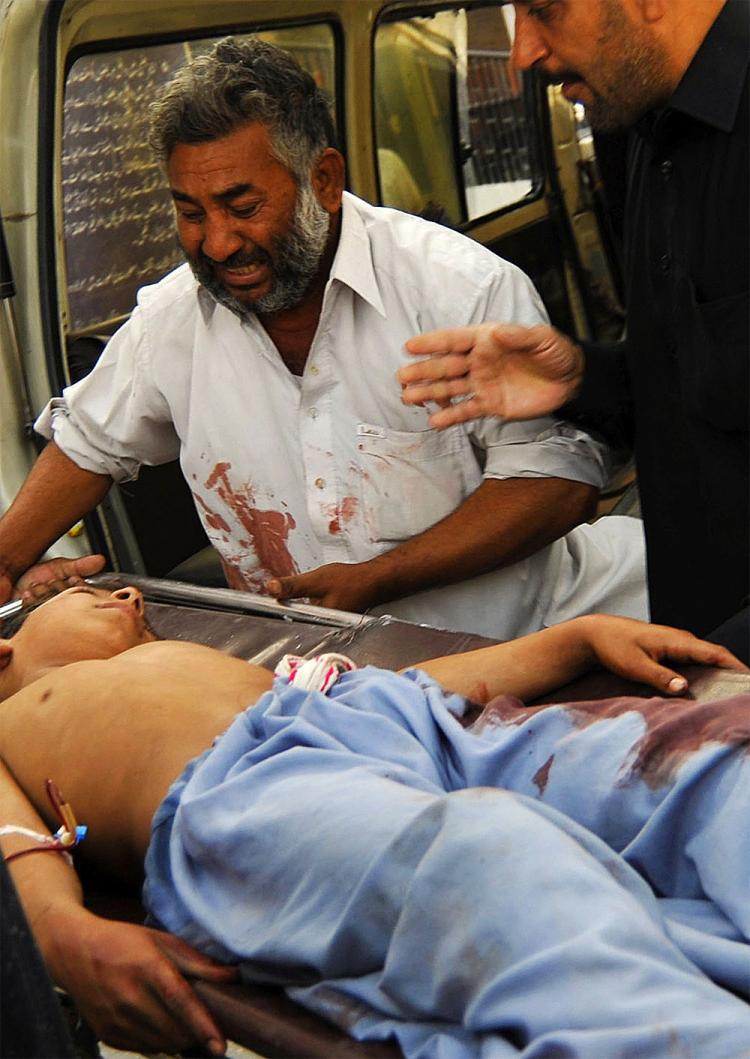 A Pakistani man (C) weeps as he carries a stretcher carrying his injured son at a hospital in Peshawar following a bomb explosion in a mosque. (Hasham Ahmed/AFP/Getty Images)