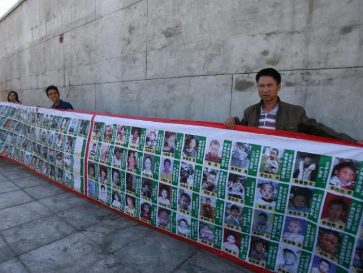 Over 30 parents from various places in China holding a large banner with photos of their children in Beijing. (Epoch Times Archive)