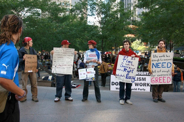 Protesters hold up signs as part of the 'Occupy Wall Street' protest at a park 500 feet from Wall Street on Sunday.  (Ivan Pentchoukov/The Epoch Times)