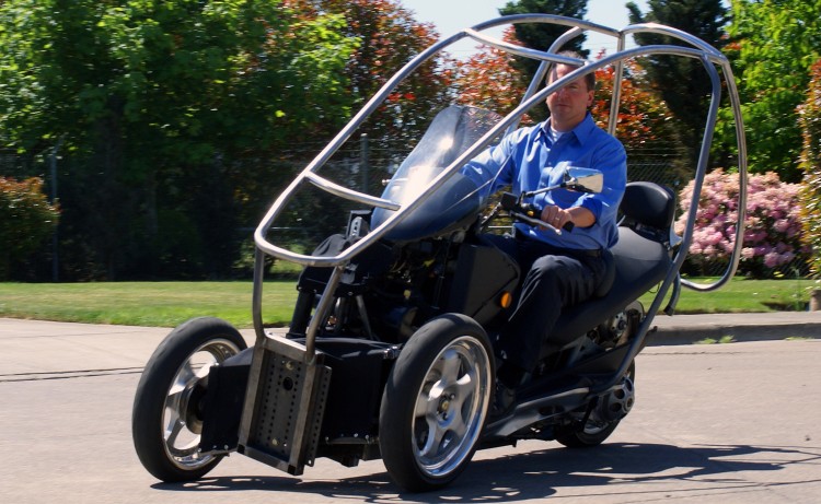 LEANING IN: Staff of Green Lite Motors take a working prototype of their new vehicle out for a test drive. The three-wheeled vehicle will have a specialized hydraulics system that lets it lean into turns like a motorcycle. (Green Lite Motors)