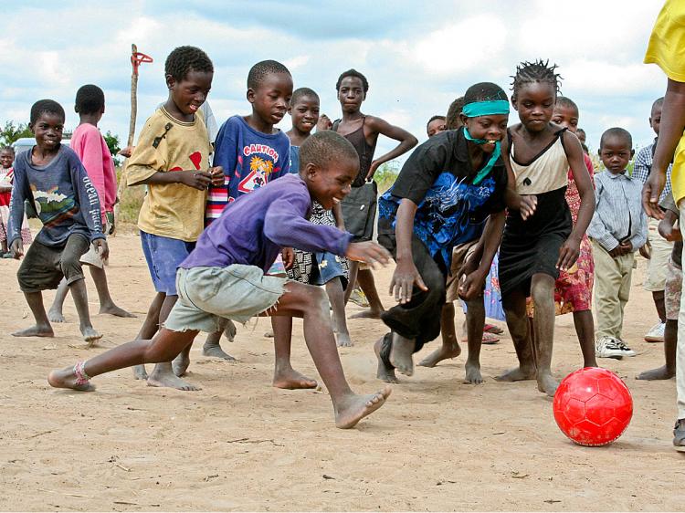 Children in Zambia have fun with Right To Play's signature red ball. The ball bears the organization's philosophy, 'Look after yourself; look after one another.' (Right To Play)