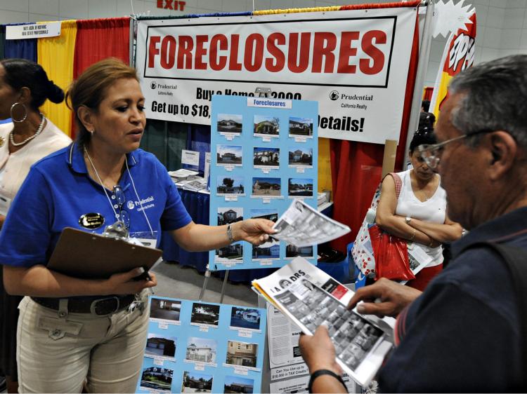 Property agents talk with customers at their stall which is advertising home foreclosures for sale, during a property fair in Los Angeles (Mark Ralston/AFP/Getty Images)