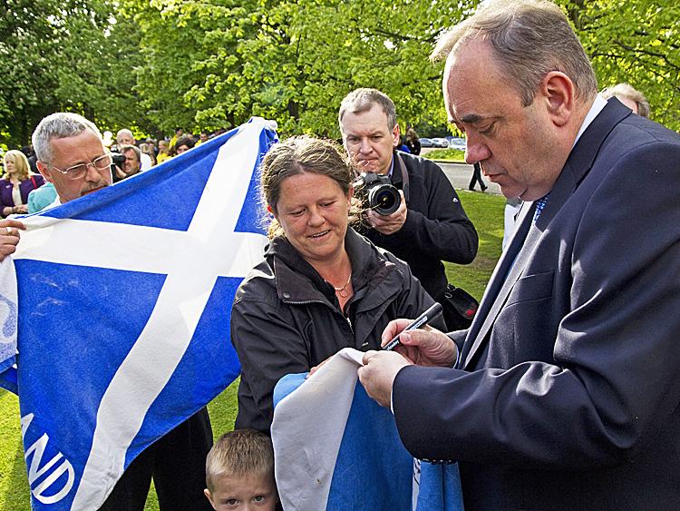 PROUD SCOT: Scottish First Minister Alex Salmond (R) autographs the Scottish national flag in Edinburgh, Scotland, on May 6. (Jonathan Mitchell/AFP/Getty Images)