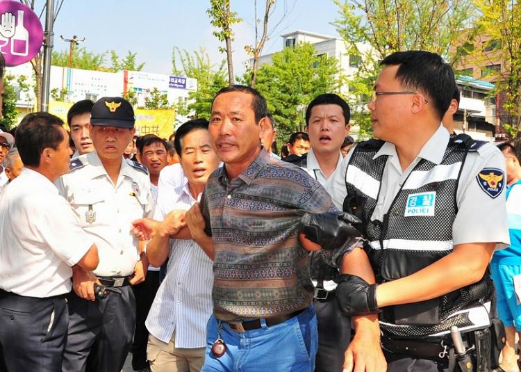 Police arrest a man attacking participants in the 'Quit the CCP' parade held in Ansan City, South Korea, on Sept. 13, 2009. (Jin Guohuan/The Epoch Times)