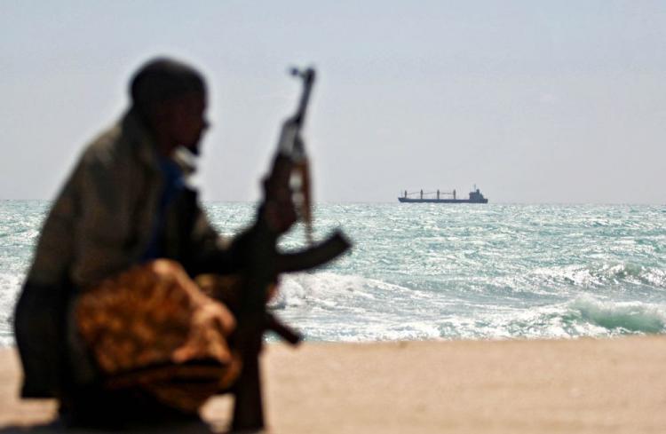 An armed Somali pirate along the coastline while the Greek cargo ship, MV Filitsa, is seen anchored just off the shores of Hobyo town in Northeastern Somalia where its being held by pirates.  (Mohamed Dahir/AFP/Getty Images)