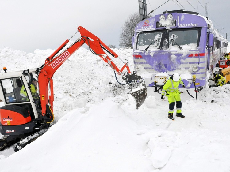 STUCK: People remove snow with an excavator from the tracks where two local trains are stuck, in Balkakra, southern Sweden in Dec. 2010. (Johan Nilsson/AFP/Getty Images)