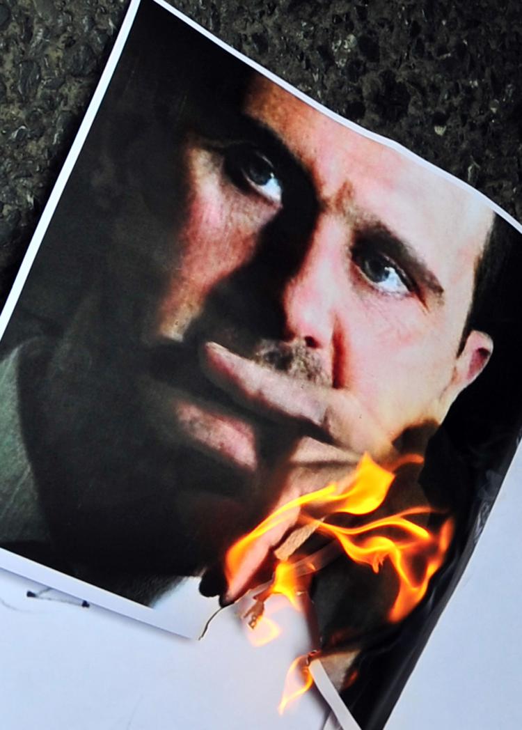 A portrait of Syrian President Bashar al-Assad is burned by protesters in a demonstration in front of the Syrian consulate in Istanbul on May 13. The U.S. on Wednesday imposed sanctions on al-Assad following weeks of heavy crackdown on protesters under his command.  (Mustafa Ozer/Getty  Images )