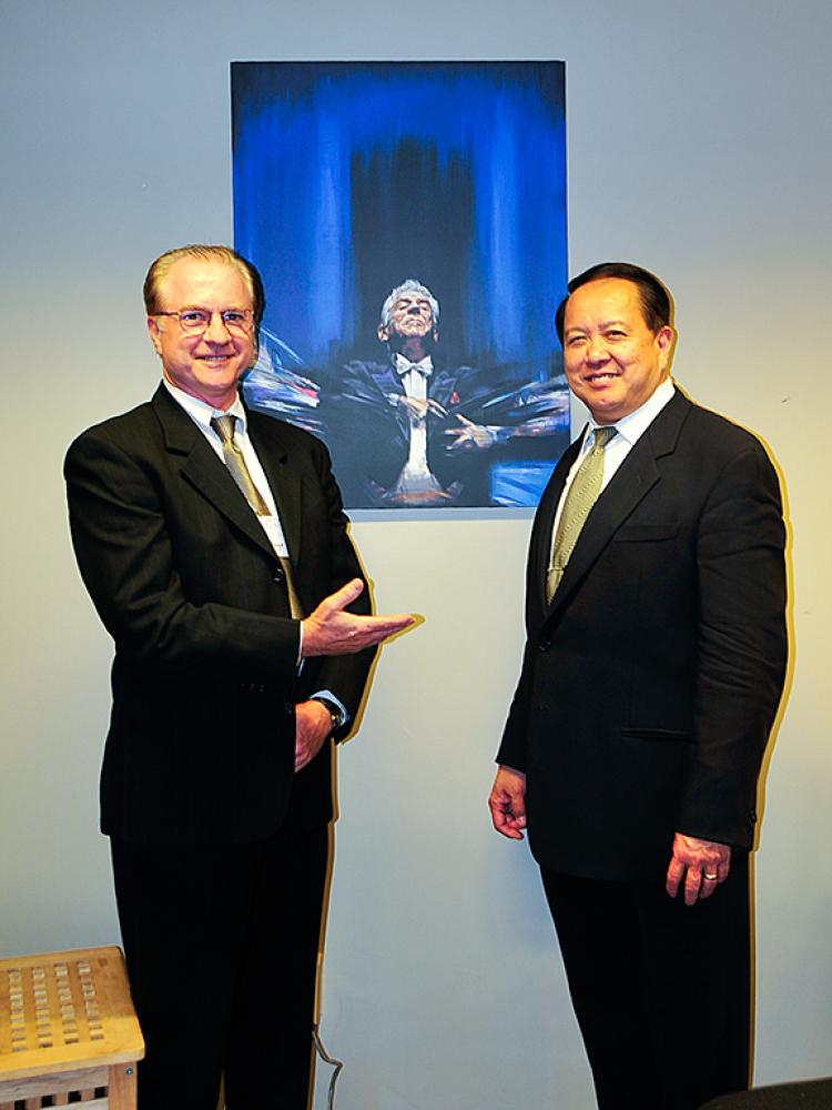 (L-R) George Stamm and Mr. Ling stand in front of a picture of the conductor's beloved mentor, Leonard Berstein. (Xusheng Li/Epoch Times)