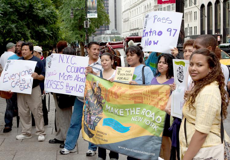 Activists and workers rally in front of the horse carriages at Central Park on Wednesday July 14 to urge City Council to bring intro 97, the Paid Sick Time Act, to a vote. (Henry Lam/The Epoch Times)