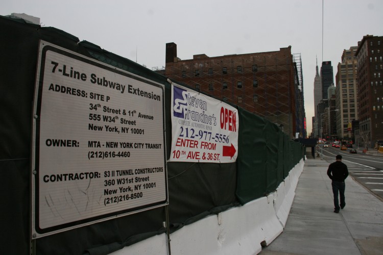 A sign for the West 7-Line Subway Extension, next a sign letting customers know Steven Francine's auto shop is still open, with an alternative entrance. (Zack Stieber/The Epoch Times) 