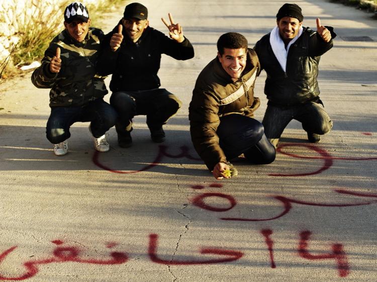 TASTING FREEDOM: Tunisian immigrants who arrived on the Italian island of Lampedusa recently pose on Feb. 15. in front of words written on a road sign reading 'Tunisia, hurray democracy, 4 January.' (Roberto Salomone/AFP/Getty Images)