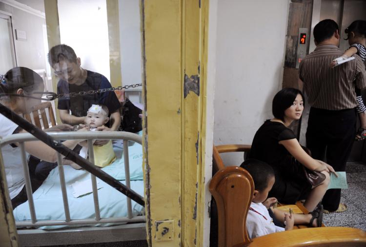 HEALTH CRISIS: Parents play with a baby who suffers from kidney stones after drinking tainted milk powder, while another family waits at the Chengdu Children's Hospital in Chengdu of Sichuan Province, China. (China Photos/Getty Images)