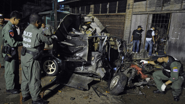 Thai bomb squad unit members inspect the wreckage of a car