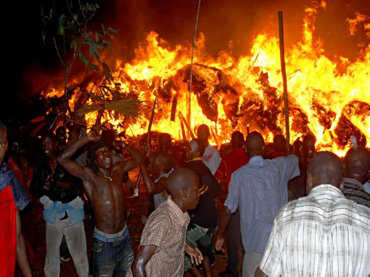 Supporters of Ronald Muwenda Mutebi II, traditional ruler of the Baganda, one of Uganda's main tribes, shout as they watch the Kasubi tombs go up in flames in the early morning on March 17 on the outskirts of Kampala. (Stringer/AFP/Getty Images)