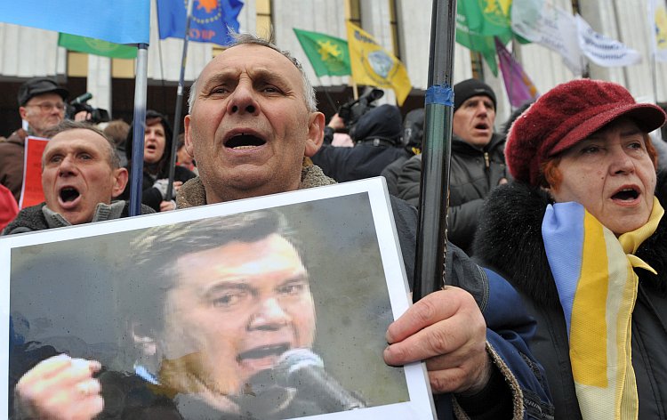 People hold placards against President Viktor Yanukovych