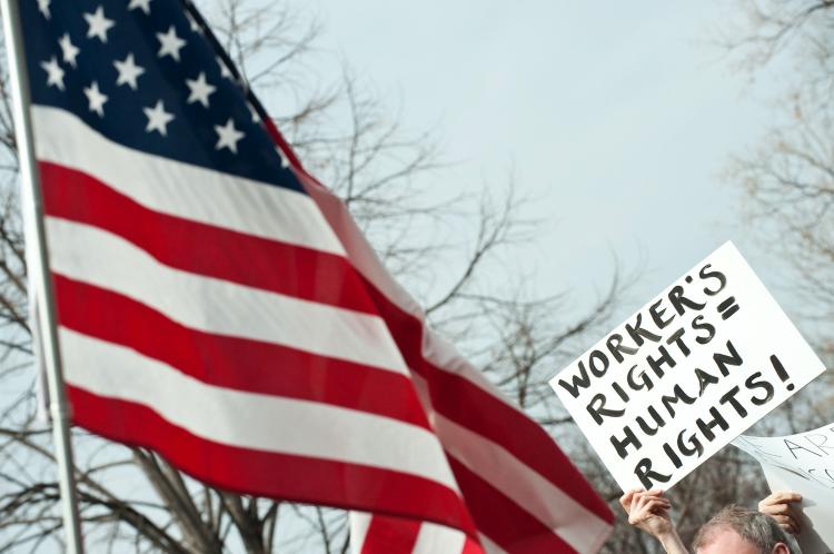 WORKERS RIGHTS: A protester holds up a sign equating worker's rights with human rights during a rally in support of Wisconsin workers Feb. 26 in Washington. The debate over public vs. private worker wages and benefits is taking place around the nation. (Nicholas Kamm/Getty Images)