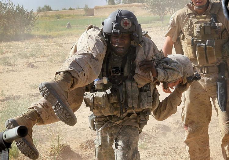 U.S. Army flight medic Sgt. Tyrone Jordan, attached to Dustoff Task Force Shadow of the 101st Combat Aviation Brigade, carries a Marine wounded by an explosive blast to a MEDEVAC helicopter near Marja, Afghanistan. (Scott Olson/Getty Images)