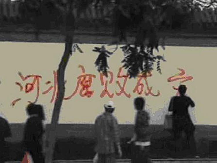 Zhao Chunhong, a pregnant petitioner in Beijing, paints an anti-corruption slogan on a wall on the street.  (The Epoch Times)