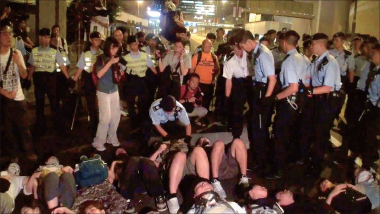 Ms. Cai Wenwen (dressed in dark blouse and white pants and holding a camera), an intern reporter from NTDTV, was arrested by police while photographing a protest in Hong Kong on the night of July 1.  (Internet Image)