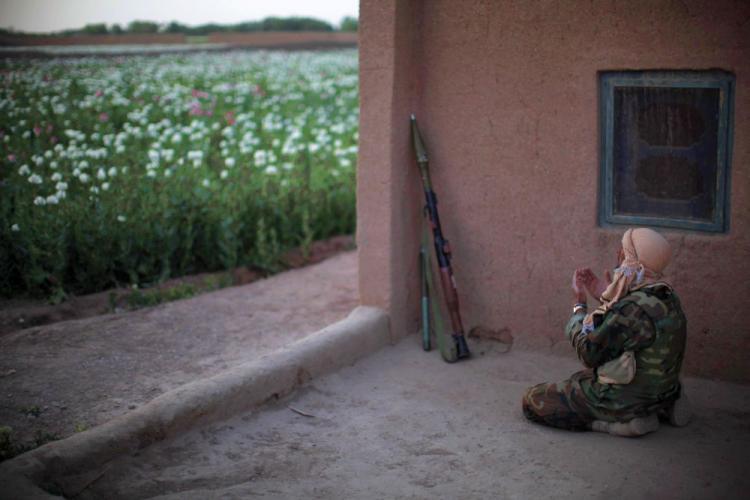 An Afghan National Army soldier prays during a foot patrol with unseen US Marines from India Company, 3rd Battalion, 6th Marines near a poppy field in a stronghold Taliban area of Marjah, Helmand province, southern Afghanistan, on April 5.
