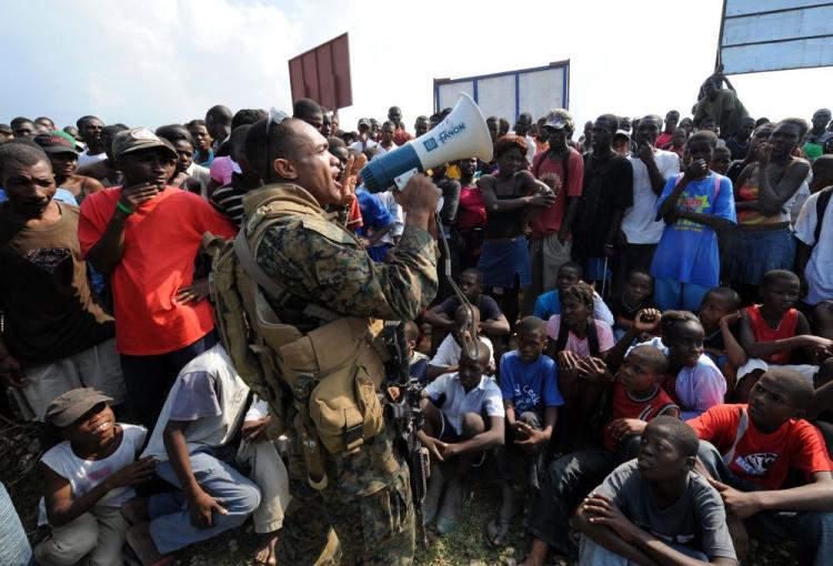 Haitian earthquake victims listen to a U.S. Marine in Leogan on Jan. 20. The logistics of transporting needed supplies is an ongoing dilemma in Haiti which was hit by a 6.1 magnitude aftershock early Wednesday morning.  (Jewel Samad/AFP/Getty Images)