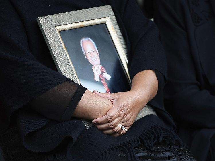 Daughter Donna Grant holds a photo of Sir Howard Morrison during his the burial service at the Kauae cemetery on September 29, 2009 in Rotorua, New Zealand. (Hannah Johnston/Getty Images)