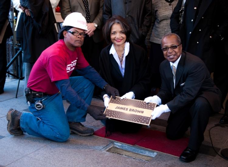 The first star of the Apollo Theater's Walk of Fame is installed for James Brown by (L-R) a construction worker, Apollo Theater's President and CEO Jonelle Procope, and Historian Billy Mitchell. (Aloysio Santos/The Epoch Times)