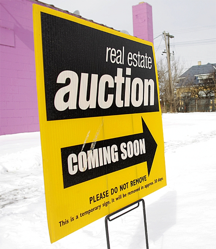 A sign announcing a coming real estate auction stands on a street corner in Detroit, Michigan. (Bill Pugliano/Getty Images)