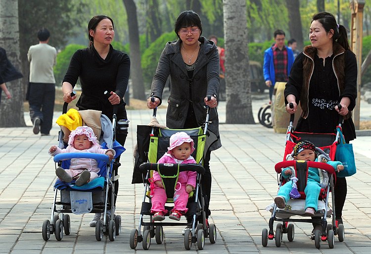 Women push babies in strollers through a Beijing park