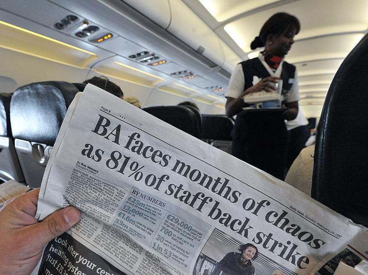 A man reads a newspaper on board of a plane during a flight from London's Heathrow airport, on February 23, 2010. (Carl De Souza/AFP/Getty Images)