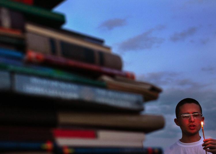 A Bulgarian student holds a candle and sings the Bulgarian National anthem behind a wall of books. (Boryana Katsarova/AFP/Getty Images)