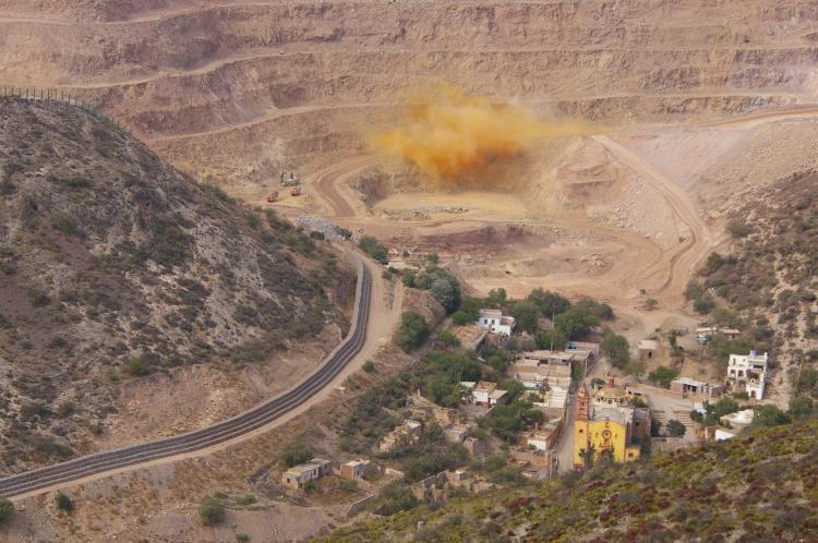Rock blasting at the Cerro de San Pedro open-pit gold and silver mine in Mexico. The town buildings can be seen in the forefront.