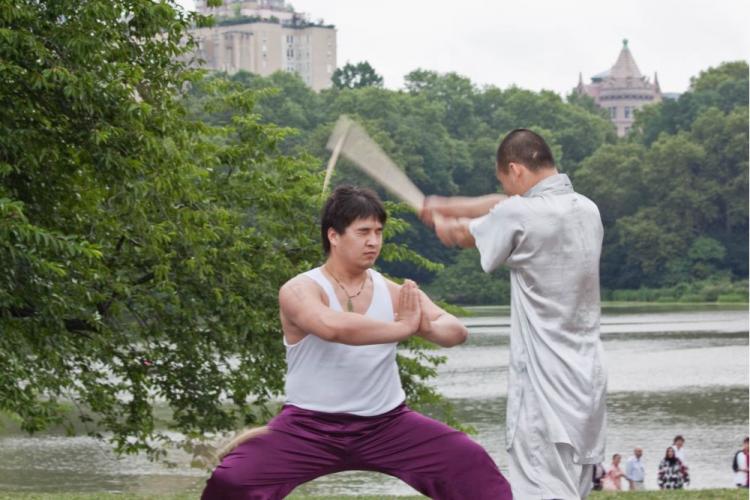 Monk demonstrates his skills by having someone break a bamboo stick on his head at Central Park on Thursday.  (Cliff Jia/The Epoch Times)