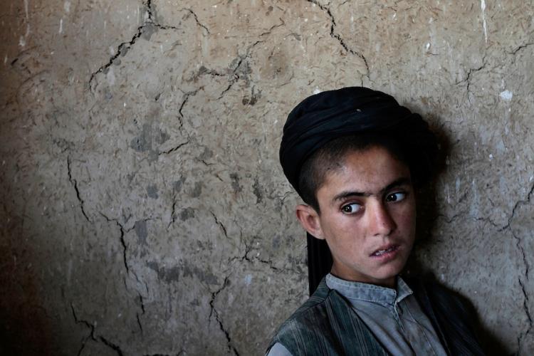 Nakeeb, a 13-year-old Pashtun Afghan boy, watches American and Canadian soldiers as they patrol on June 9, in the village of Zor Mashur, Afghanistan. The Soldiers are a part of a counterinsurgency strategy aimed at protecting Afghan civilians.  (Chris Hondros/Getty Images)