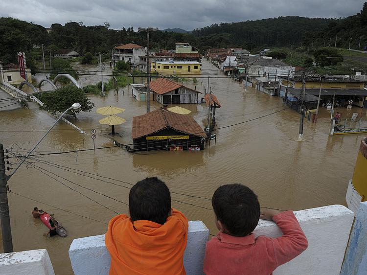 Children look at residents evacuating a dog on a kayak at a flooded area in downtown Franco da Rocha, some 35 kilometers west of Sao Paulo, Brazil, on January 12, 2011. (Mauricio Lima/AFP/Getty Images)