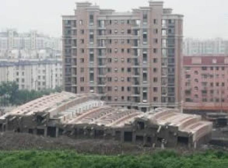 A 13-story residential building under construction in Shanghai toppled over at around 6 am on June 27, 2009, killing one worker. (The Epoch Times)