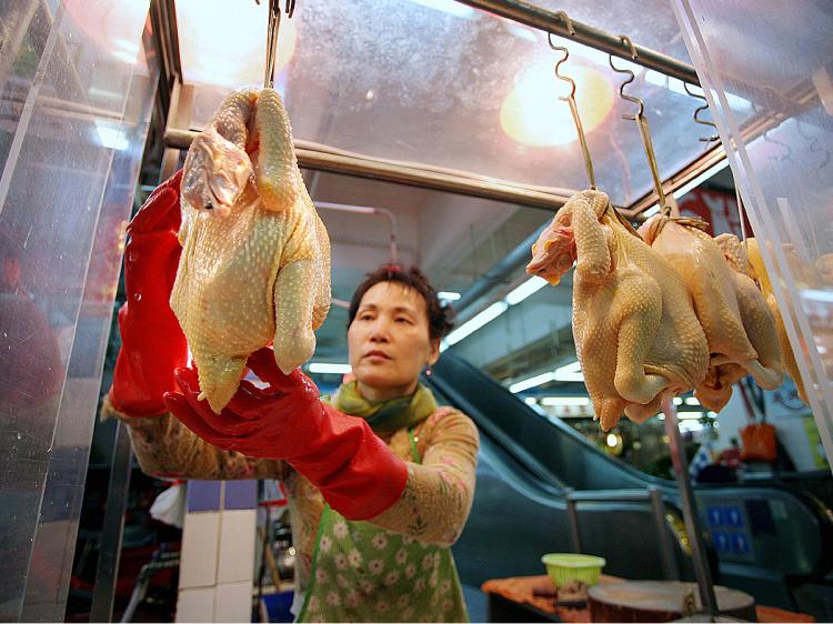 A poultry vendor weights sells cooked chickens at a market in Hong Kong. (Samantha Sin/AFP/Getty Images)