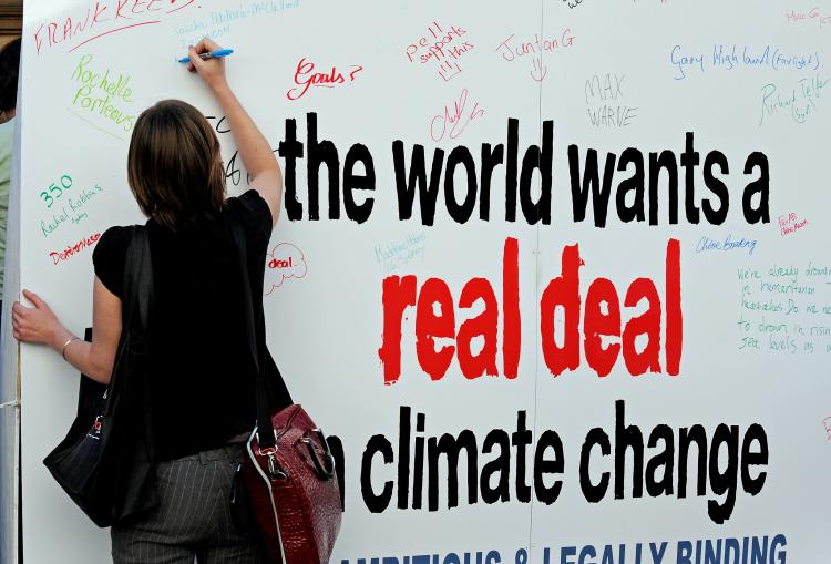 A climate action activist signs a large placard alongside a gathering of other activists on the Sydney Town Hall steps for a silent 'Vigil of Hope' on Dec. 11, 2009. (Greg Wood/AFP/Getty Images)
