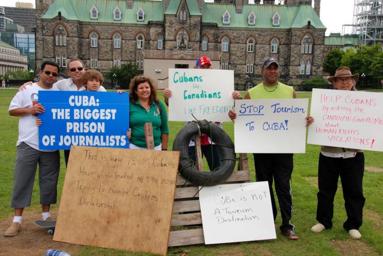 (L-R) Nelson Taylor, Miguel Figuerola and his son Dennis and wife Susana Gonzalez, Lazaro Gonzalez (no relation), Juan Carlos, and Asdrubal Caner pose with a makeshift raft. (Pam McLennan/The Epoch Times)
