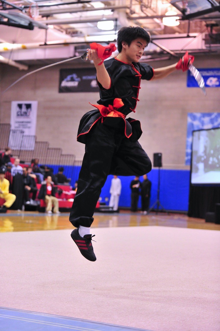 Clint Wu, a silver-medal winner in the male weapons category, performs the rolling double broadsword. (Dai Bing/The Epoch Times )