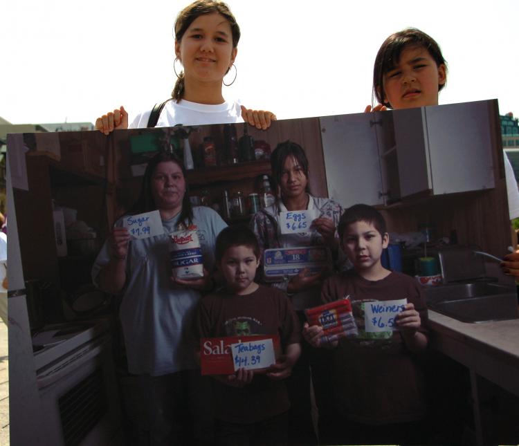 Two Aboriginal girls carry a picture of a family from Northern Canada. The picture highlights the high price of basic food stuffs faced by many in Canada's far North. (Matthew Little/Epoch Times Staff)