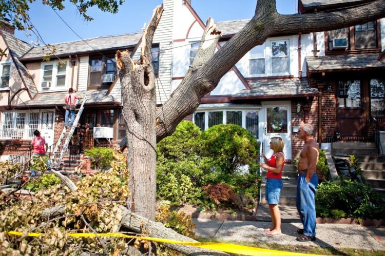 Donna-Marie Goedtel and neighbour, Teddy Cleanthes, look on as workers repair damage done to Goedtel's Forest Hills home.  (The Epoch Times)