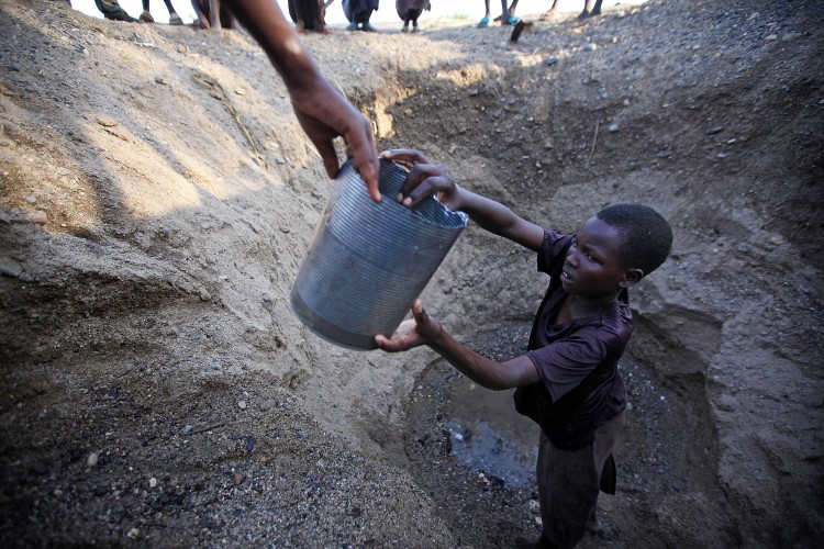 DIGGING FOR WATER: Children in northern Kenya dig a hole in a river bed to retrieve water. Drought has an enormous impact on communities around the world, and according to the U.N. is only expected to increase. (Christopher Furlong/Getty Images)
