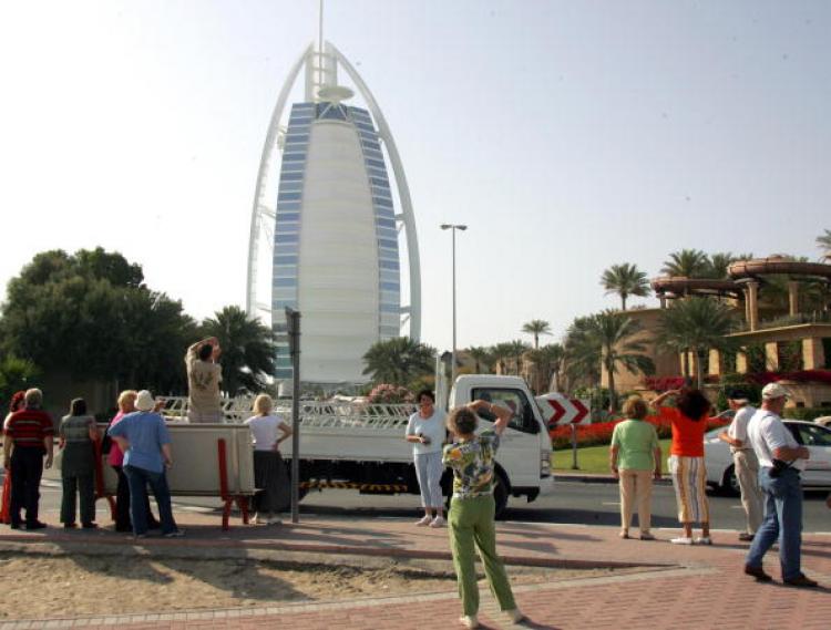European tourists take pictures of the Burj al-Arab (L) and Jumeirah Beach Hotel in Dubai.  (Rabih Moghrabi)