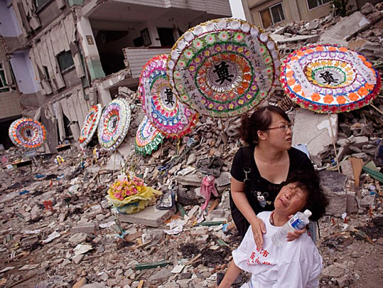 A woman whose child was killed when the Xinjian primary school collapsed in the May 12 earthquake, is comforted by a relative as she is overcome by grief during a commemoration of Children's Day on the rubble-strewn school campus on June 1, 2008 in Dujian (Andrew Wong/Getty Images)