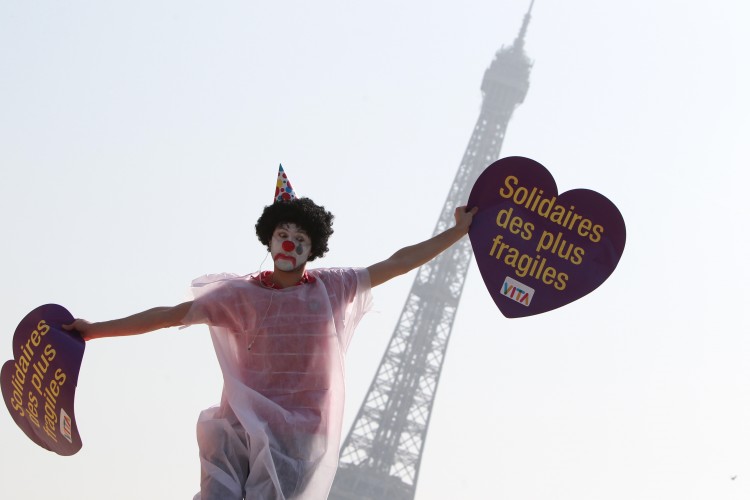 'IN SOLIDARITY WITH THE WEAKEST PEOPLE': A protester dressed up like a clown takes part in a flash mob event organised by the 'Alliance VITA' association as part of campaign in solidarity with elderly people and against euthanasia on March 24th, 2012 in front of the Eiffel tower in Paris. The placard reads: 'In solidarity with the weakest people'
