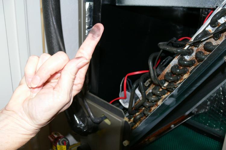 A resident shows the black residue that has formed on the copper AC coils in her Florida home. (Linda Li/The Epoch Times)