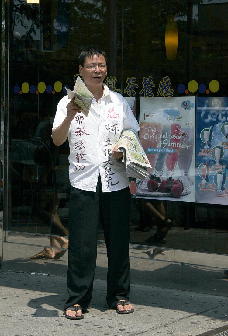 This man was seen distributing a newspaper in Flushing that listed a false office address and false PO box. The paper carries propaganda from the Chinese Communist Party that slanders the meditation practice Falun Gong. He is wearing a shirt that is covered in anti-Falun Gong slogans and he shouted defamatory remarks in Chinese as he handed out the tabloid paper. (Tim McDevitt/The Epoch Times)