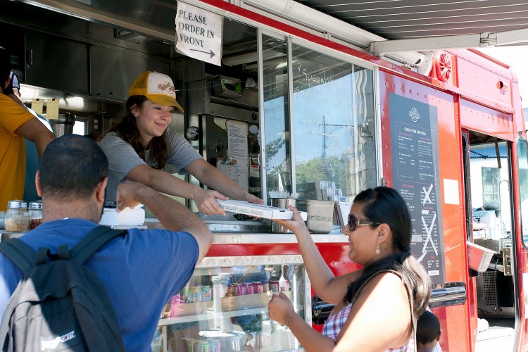 PIZZA AT THE PARK: Susana Medeiros serves pizza from Eddie's Pizza truck with a smile at Prospect Park Food Truck Rally on Sunday.  (Tara MacIsaac/The Epoch Times)